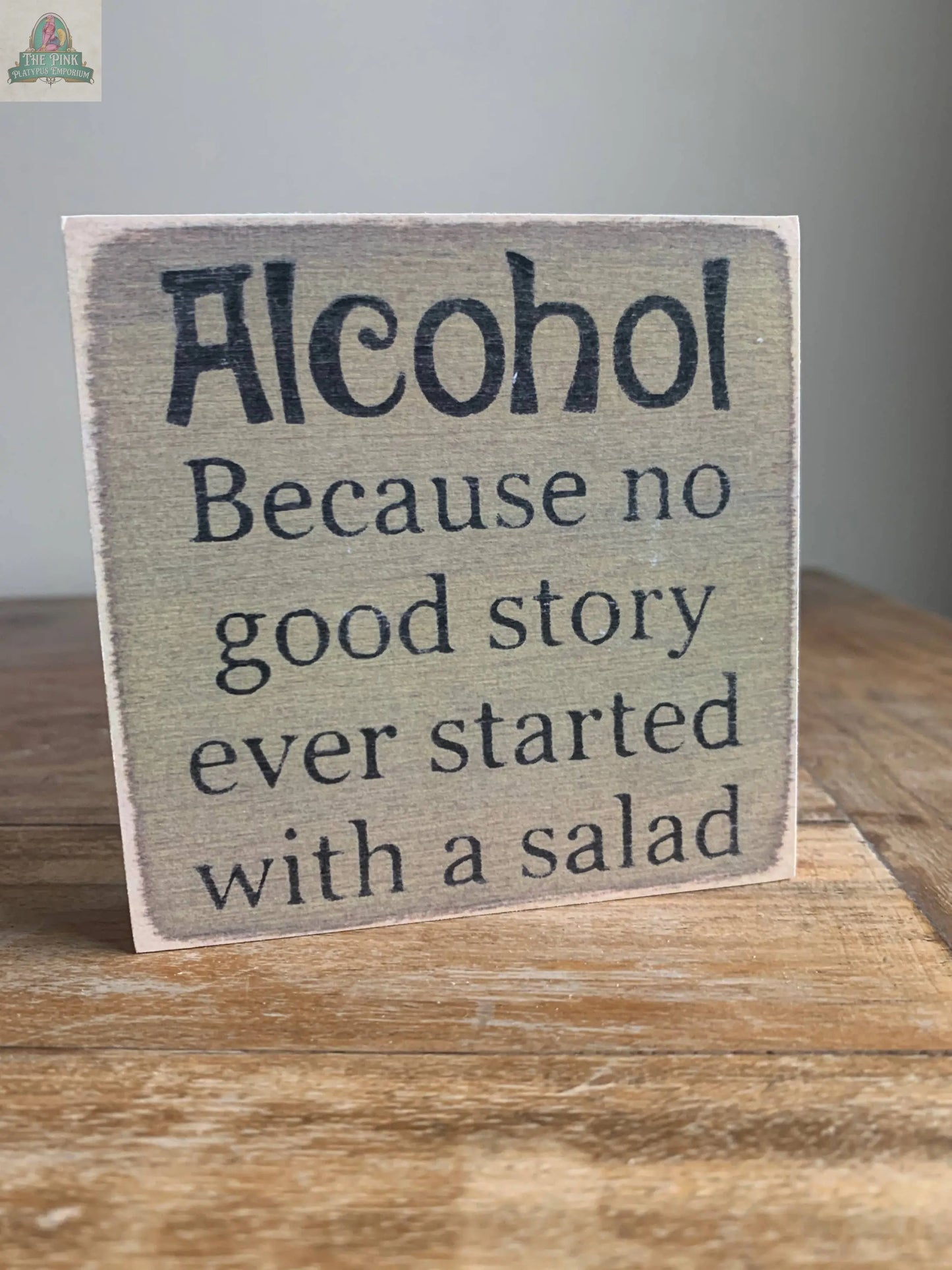 The Pink Platypus Emporium 4X4-Alcohol wooden block sign reads, "Alcohol. Because no good story ever started with a salad." Its rustic charm and neutral tones make it a perfect addition to your home decor.
