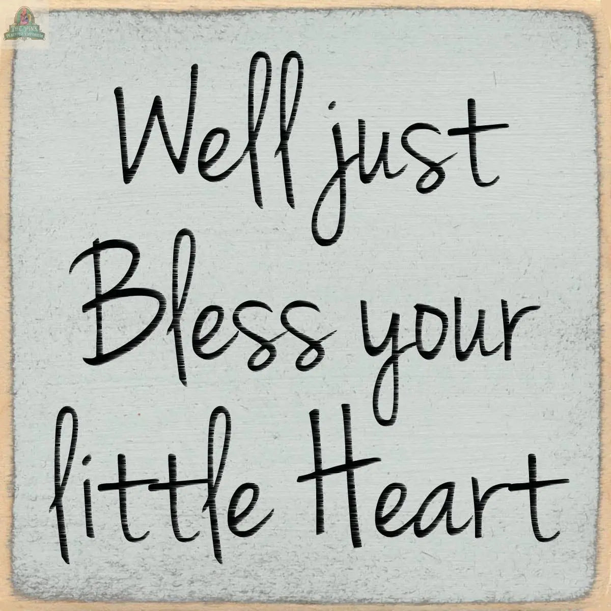 Text on a textured, light gray background reads: Well just Bless your little Heart in black, handwritten-style font. Pink Platypus Emporium’s 4X4-Bless Your Heart sign adds charm to any decor or collection of seasonal wooden block signs.