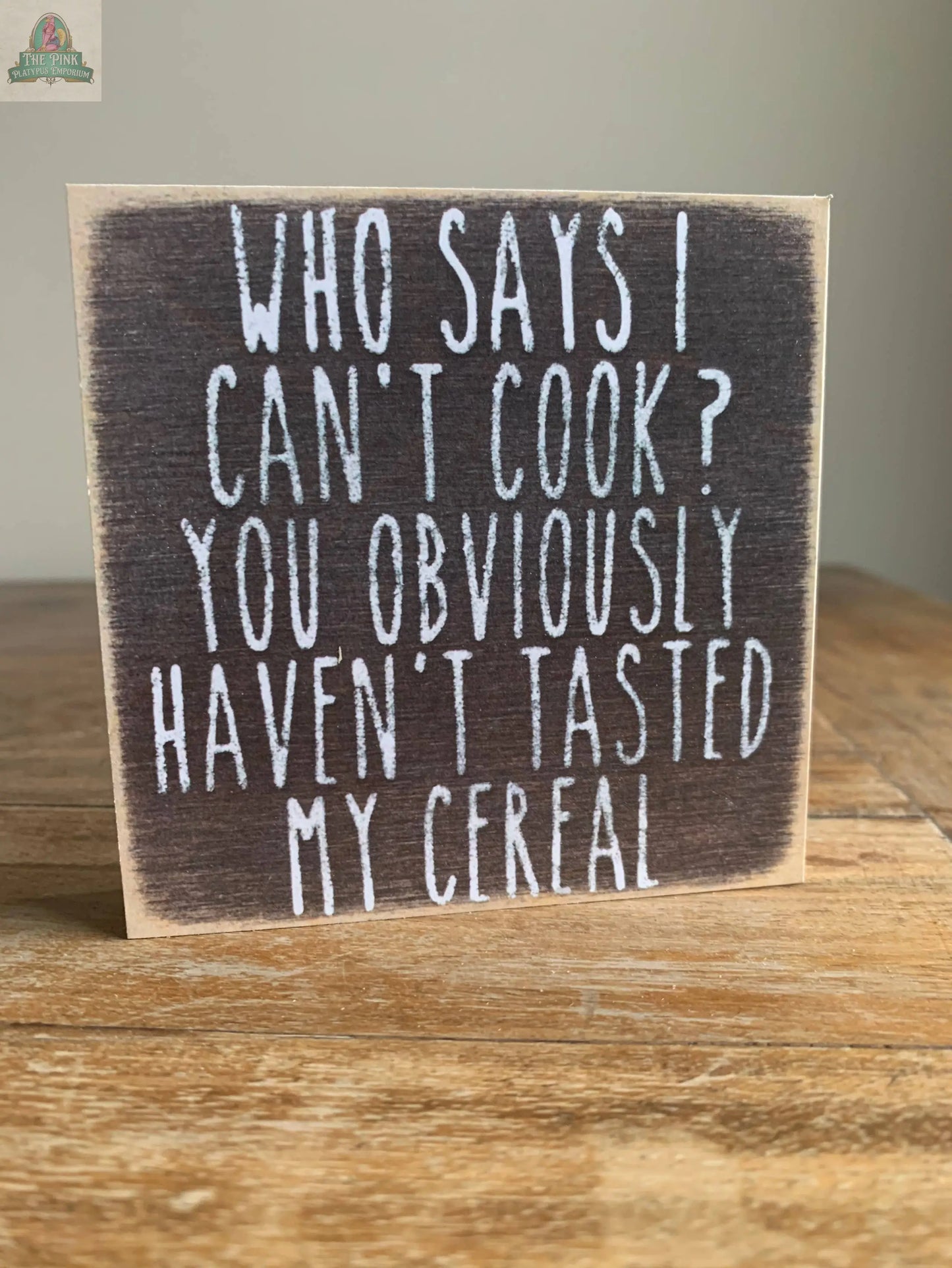 Add humor to your kitchen with Pink Platypus Emporium’s 4X4-Can't Cook wooden block sign that reads, “Who says I can’t cook? You obviously haven’t tasted my cereal.” Perfect for your home decor or seasonal sign display.