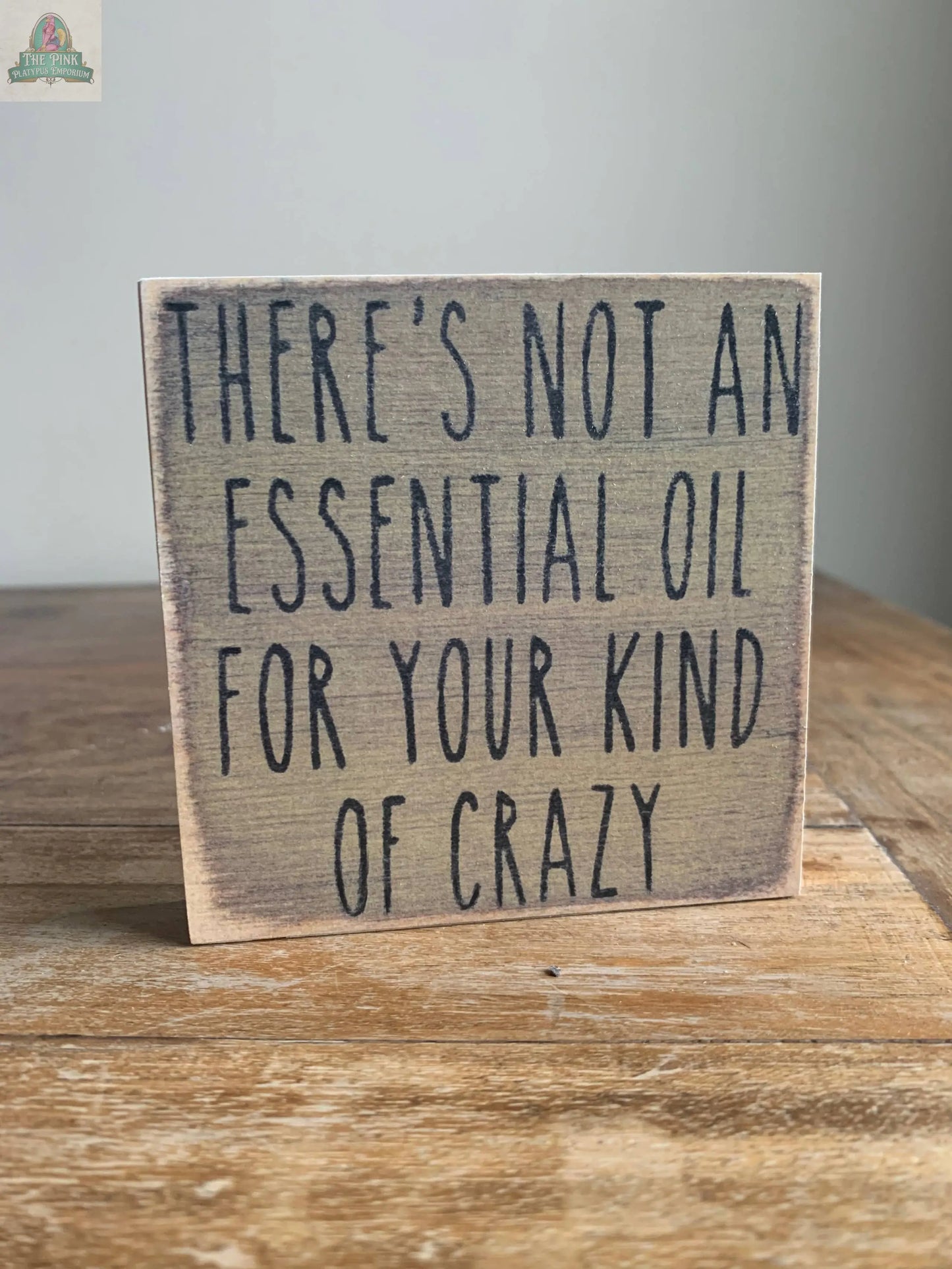 The Pink Platypus Emporium 4X4- Essential Oil wooden block sign displays "THERES NOT AN ESSENTIAL OIL FOR YOUR KIND OF CRAZY" in bold black letters—a humorous accent for any home decor.