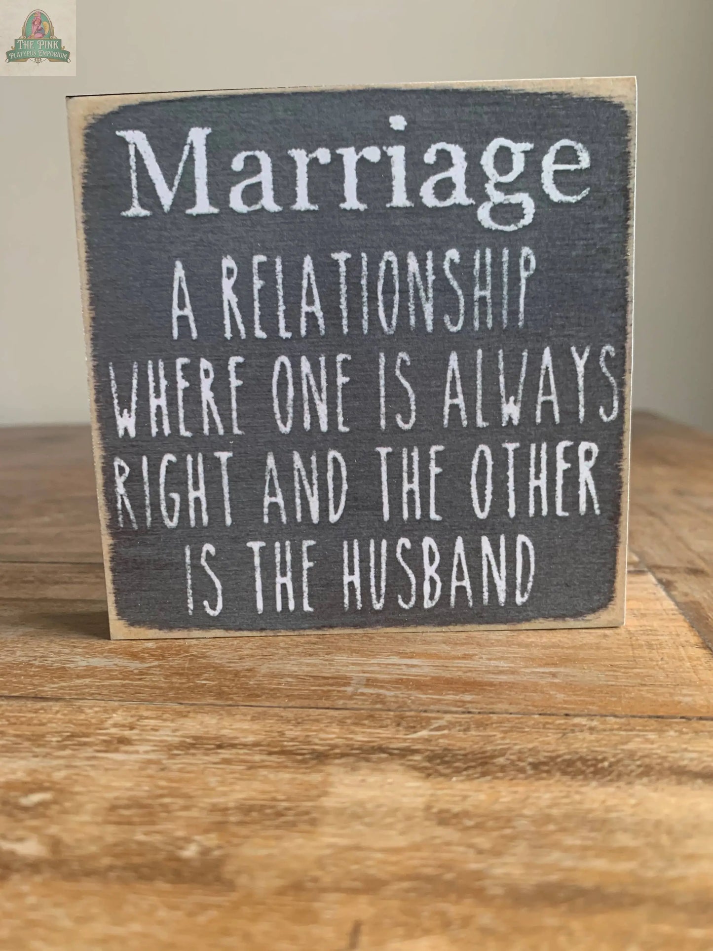 The Pink Platypus Emporium 4X4-Marriage wooden block sign humorously reads: "Marriage. A relationship where one is always right and the other is the husband"—a fun home decor piece for your seasonal sign display.