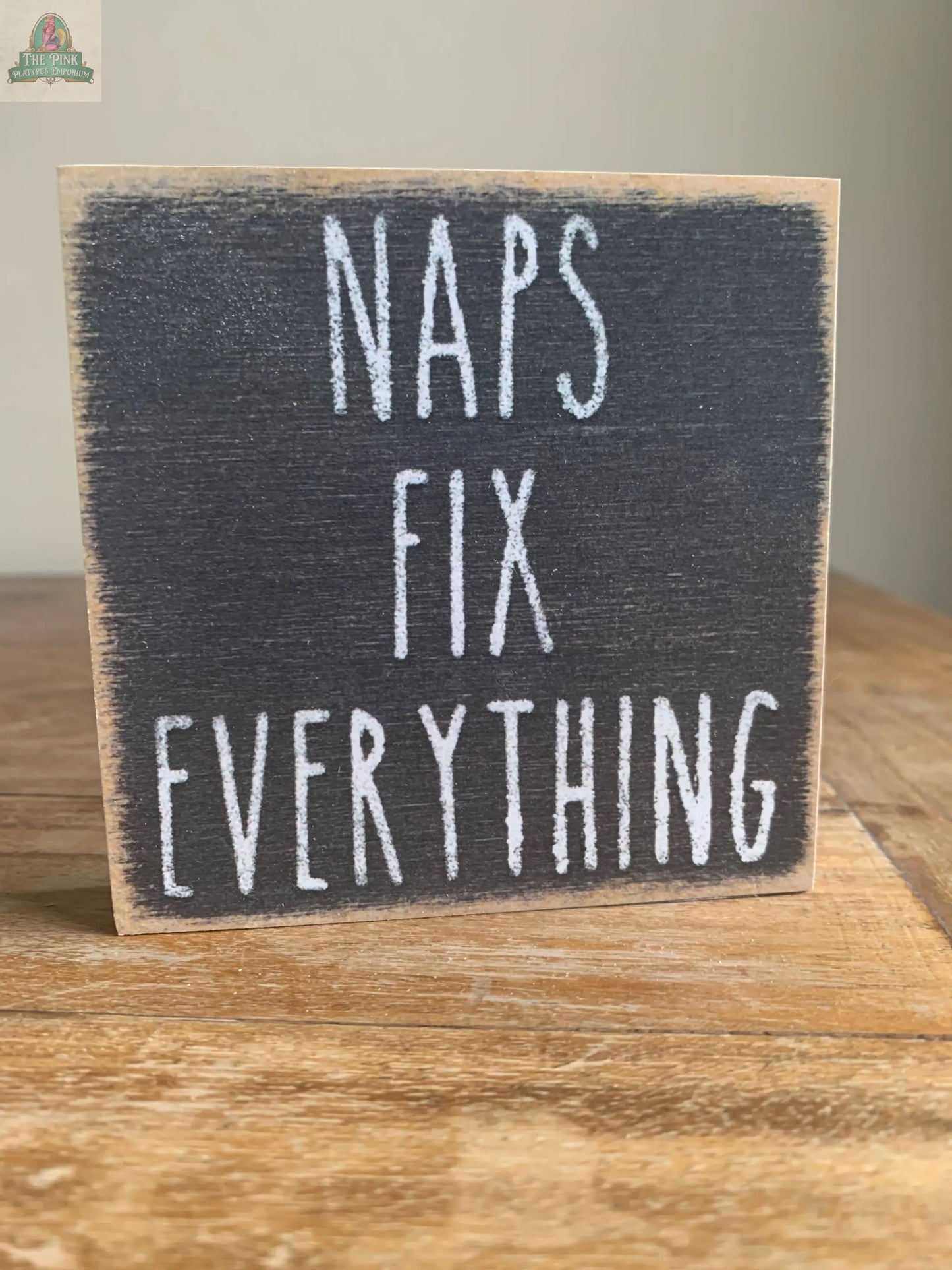 The Pink Platypus Emporium 4X4-Naps Fix sign features “NAPS FIX EVERYTHING” in white, chalk-style letters on a dark background—ideal for cozy home decor or adding charm to your seasonal block sign display.