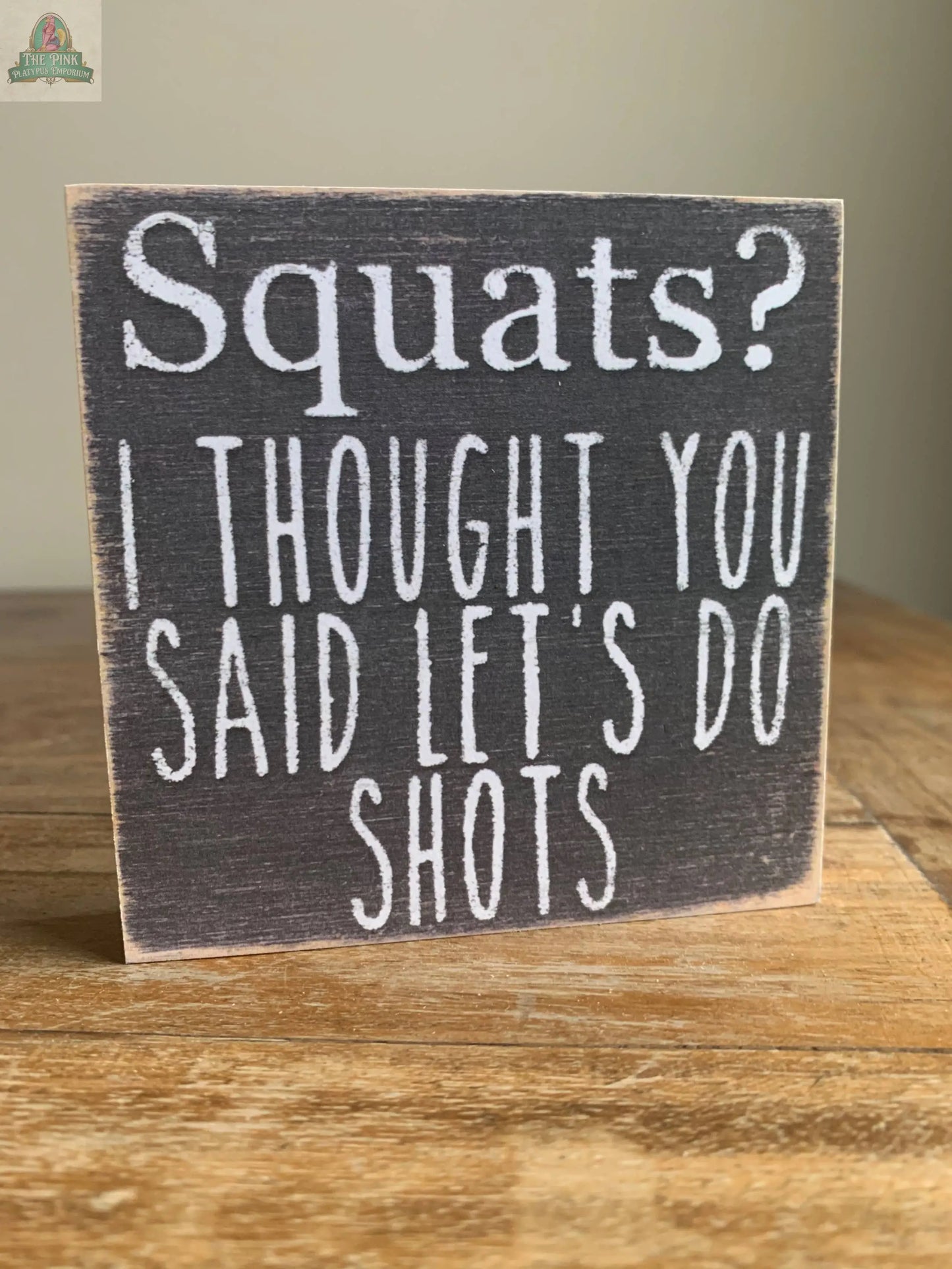 The Pink Platypus Emporium 4X4-Squats wooden block sign features playful white text: "Squats? I thought you said let’s do shots"—a fun home decor accent, ideal for seasonal displays.