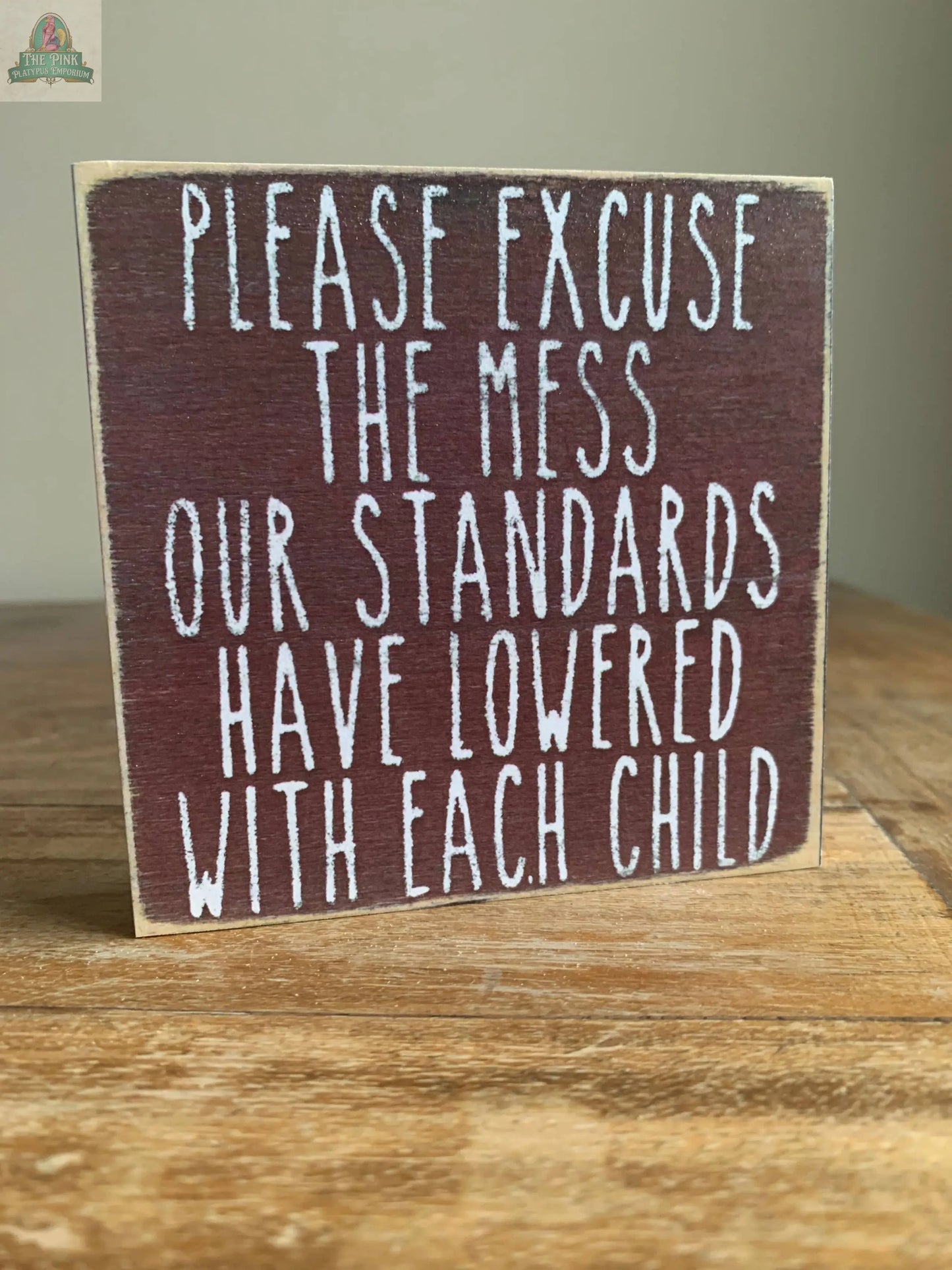 The Pink Platypus Emporium 4X4-Standards Lowered block sign features "Please excuse the mess. Our standards have lowered with each child" in white on dark brown—a witty wooden decor piece for your home.