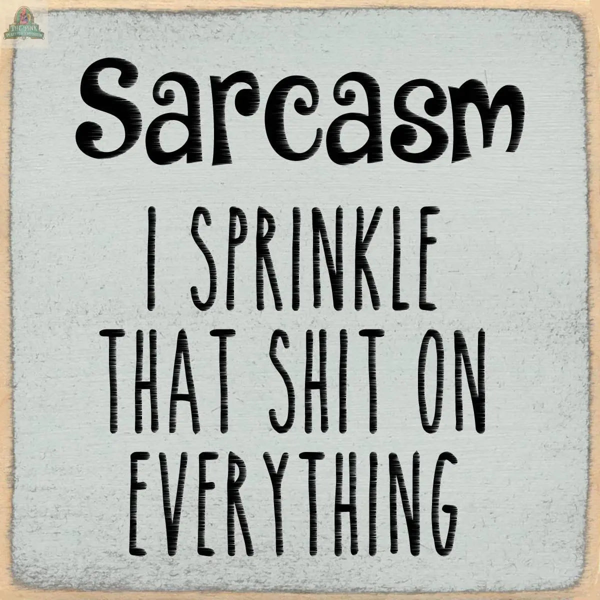 The Pink Platypus Emporium 4X4-Sarcasm block sign features bold, playful black text on a textured gray wooden square: "Sarcasm - I sprinkle that shit on everything.