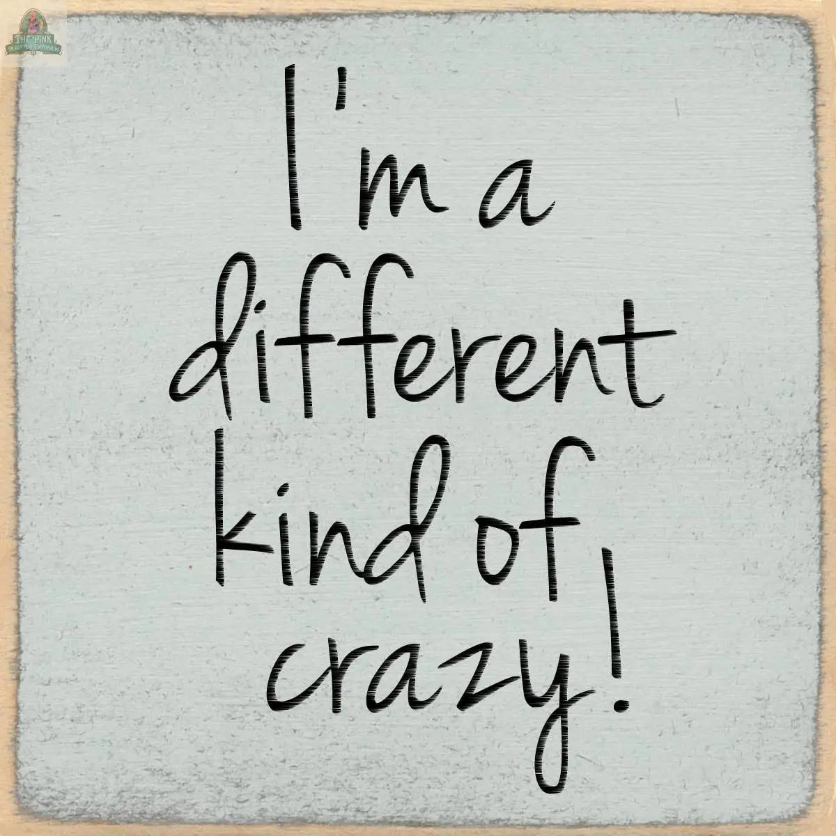 Text on a textured light gray background reads "I'm a different kind of crazy!" in a casual, handwritten-style font—perfect for adding personality with the 4X4-Kind of Crazy wooden block sign by Pink Platypus Emporium.