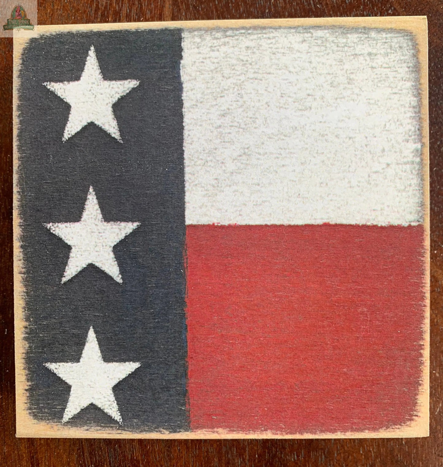 The Three Stars Americana Wood Sign by Pink Platypus Emporium features three white stars on a blue stripe with red and white stripes, making it a perfect rustic accent for Americana decor.