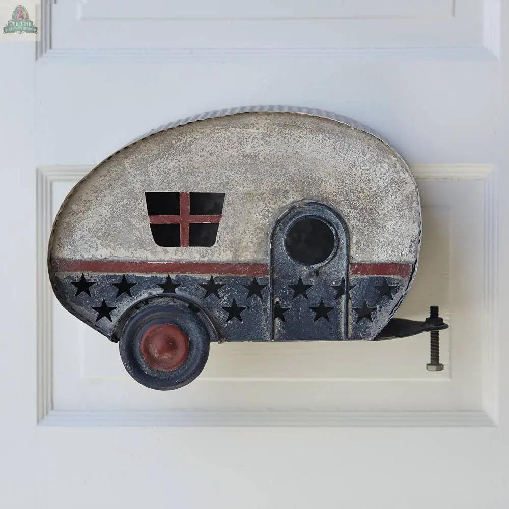 The Americana Camper Hanging Birdhouse, with star cutouts, a red and white striped window, and a small door, adds vintage camper charm to any white paneled wall.