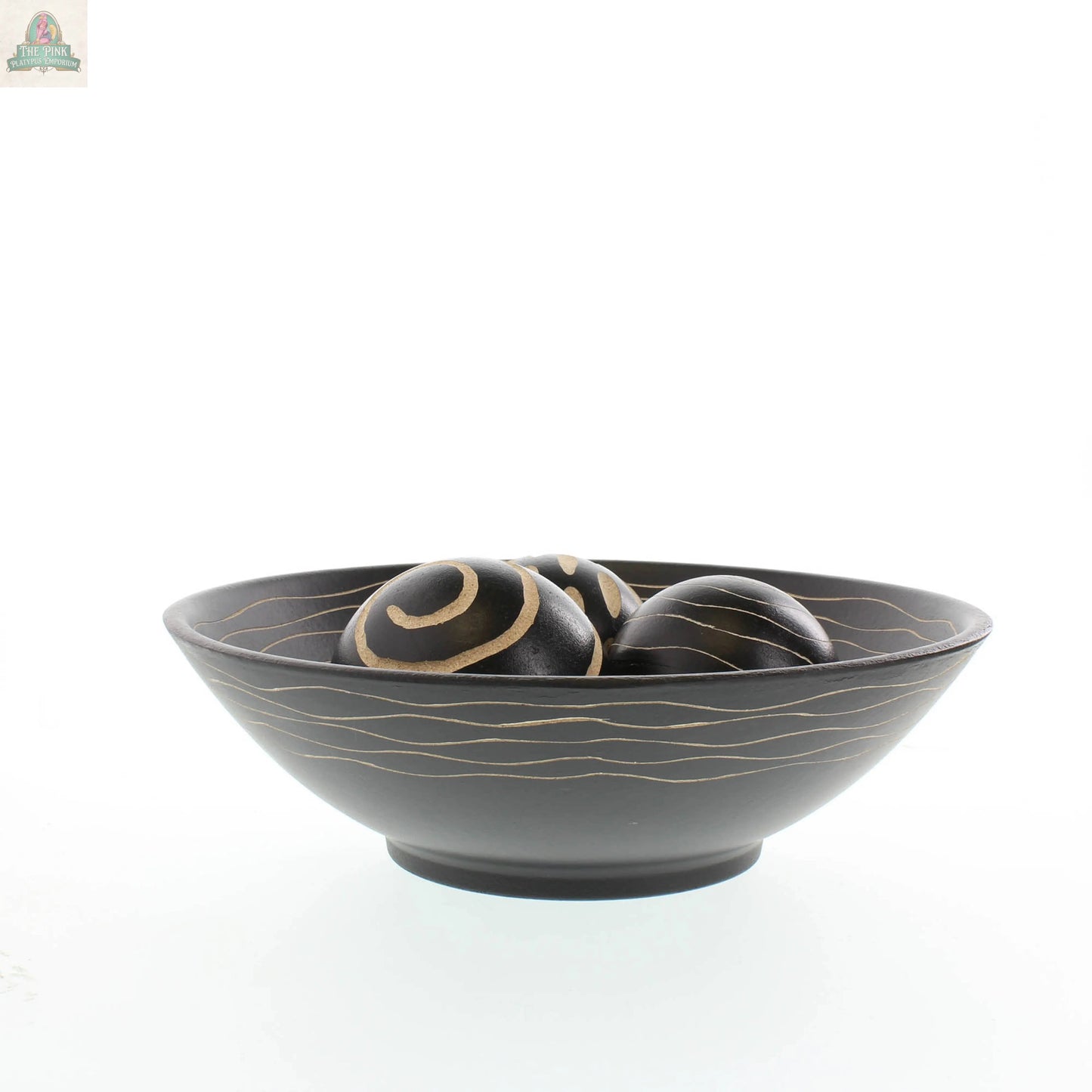 The Pink Platypus Emporium Artisan Deco Bowl and Balls set features a black bowl with thin gold waves, holding three matching decorative balls with unique gold swirl and stripe designs, displayed against a white background.