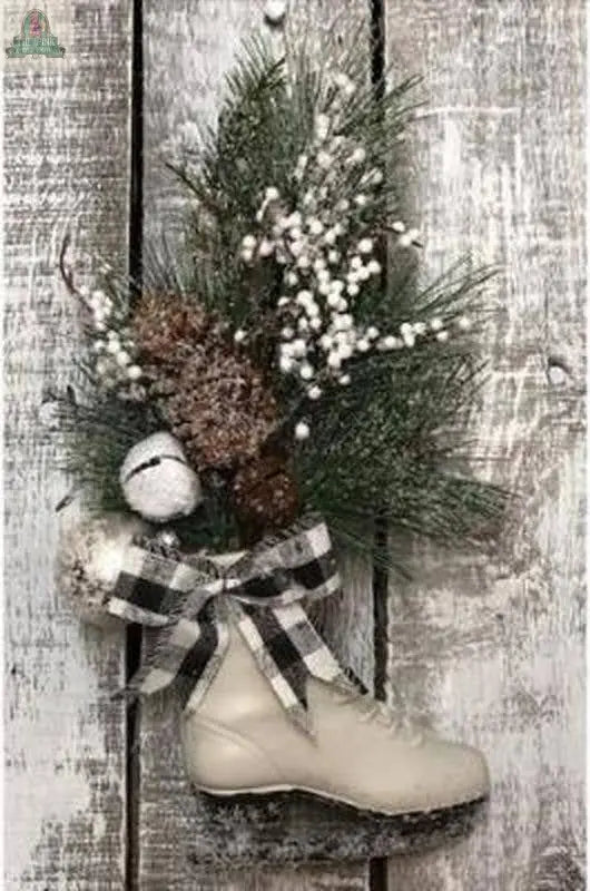 The Holiday Winter Skate Decor from Pink Platypus Emporium features a white ice skate with pine branches, pinecones, white berries, and a black and white plaid bow, perfect for hanging on rustic wooden backgrounds.