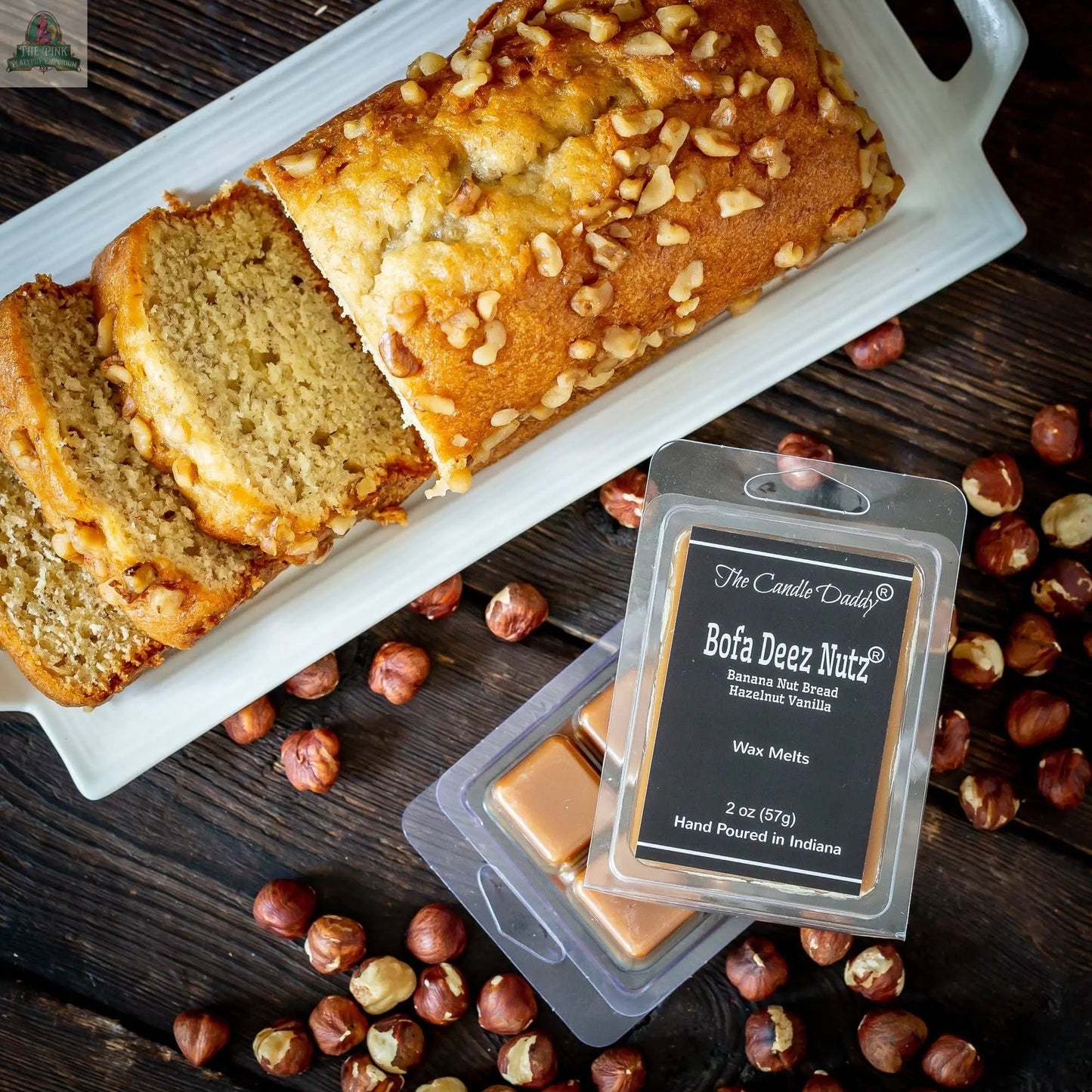 A sliced banana nut bread loaf sits on a tray with hazelnuts. In front is a pack of Bofa Deez Nutz Wax Melts - Banana Nut Bread: 1 Pack of Wax Melts, featuring banana nut bread and hazelnut vanilla scents.
