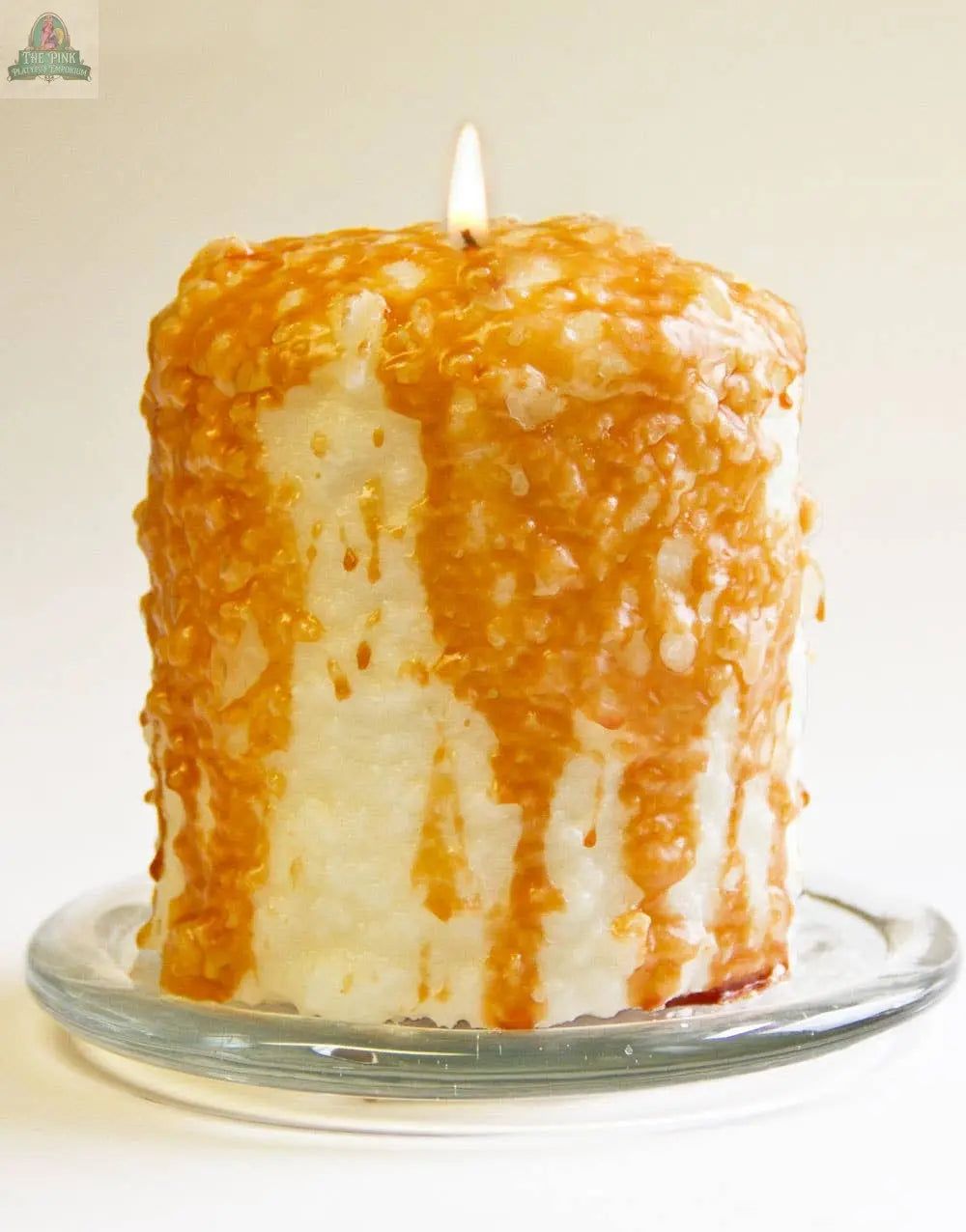 The Caramel Corn Hearth Candle, handmade in the USA, features golden caramel wax drips and a rich caramel scent. Displayed on a glass dish against a white background, it adds textured, decorative charm to any setting.