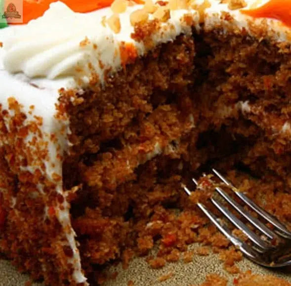 A close-up of a partially eaten carrot cake with cream cheese frosting and chopped nuts, crumbs scattered beside a fork—just like the aroma of Pink Platypus Emporium's Carrot Cake 2 Wick Loaves, a candle with an impressively long burn time.