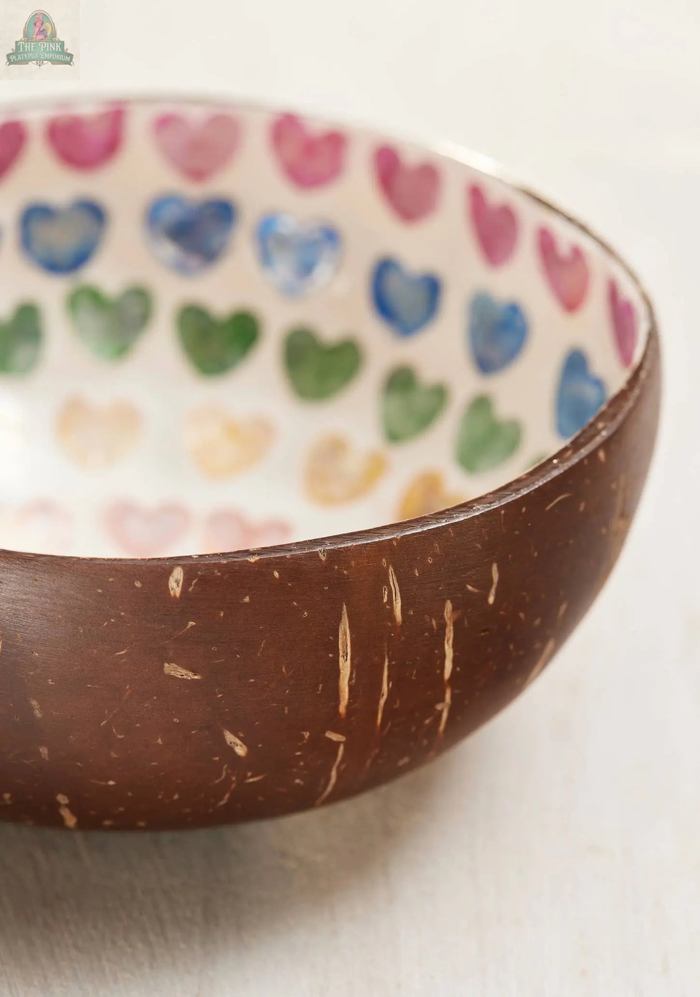 The Coconut Bowl, Shell Rainbow Heart by Pink Platypus Emporium showcases a smooth brown exterior and a hand-painted rainbow heart interior, making this Vietnamese handicraft an eco-friendly and colorful serving bowl.