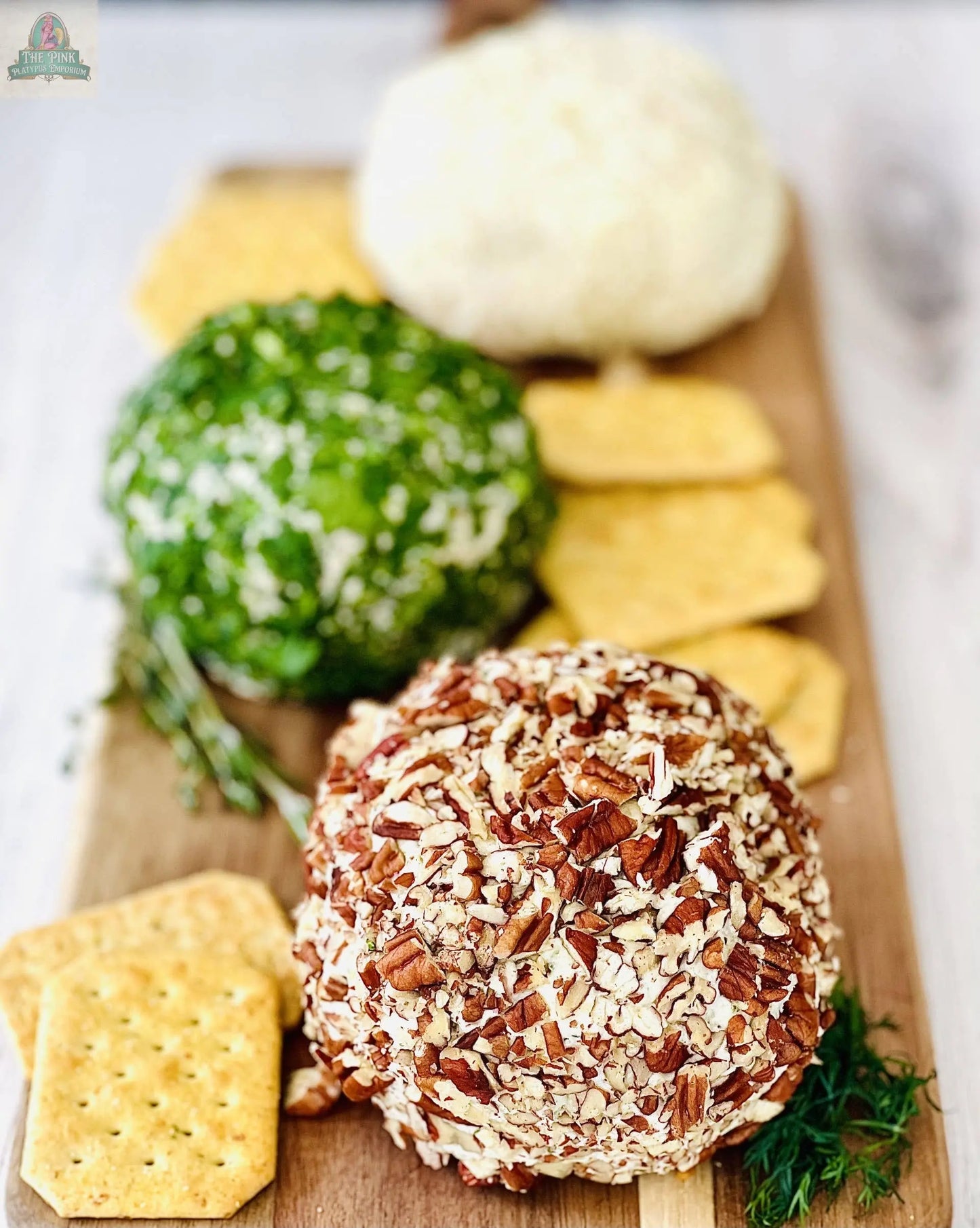 Carmies Kitchen’s Pepper Jack Appetizer Cheeseball features three cheeseballs coated in chopped nuts, herbs, and cheese on a wooden board with crackers—an inviting appetizer perfect for pairing with your favorite dip mix.