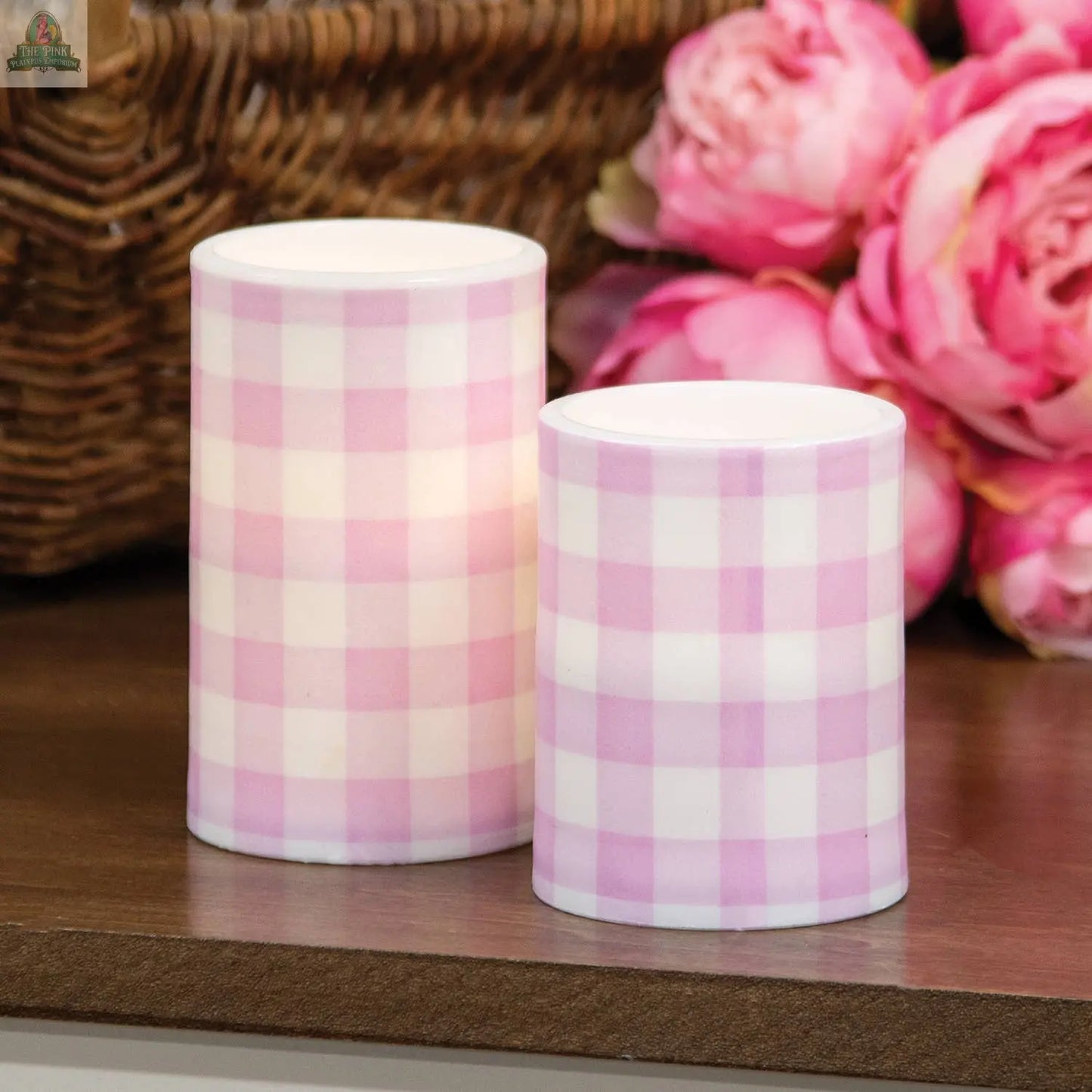 The Pink Platypus Emporium Pink Gingham Check Timer Pillar (3"x5") adds country charm to any space, featuring a pink and white checkered flameless design—perfect beside flowers and a woven basket for cozy decor.