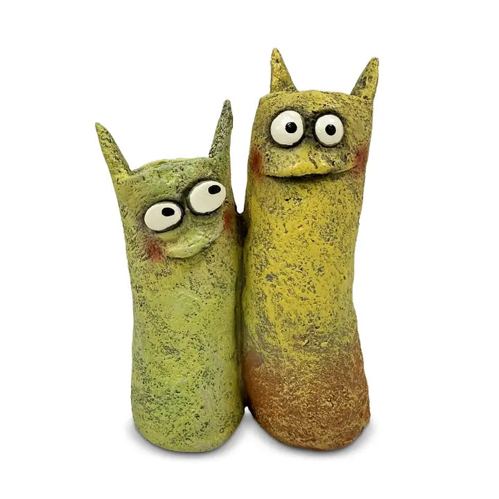 Two green and brown ceramic cat-shaped succulent planters with large eyes on a white background