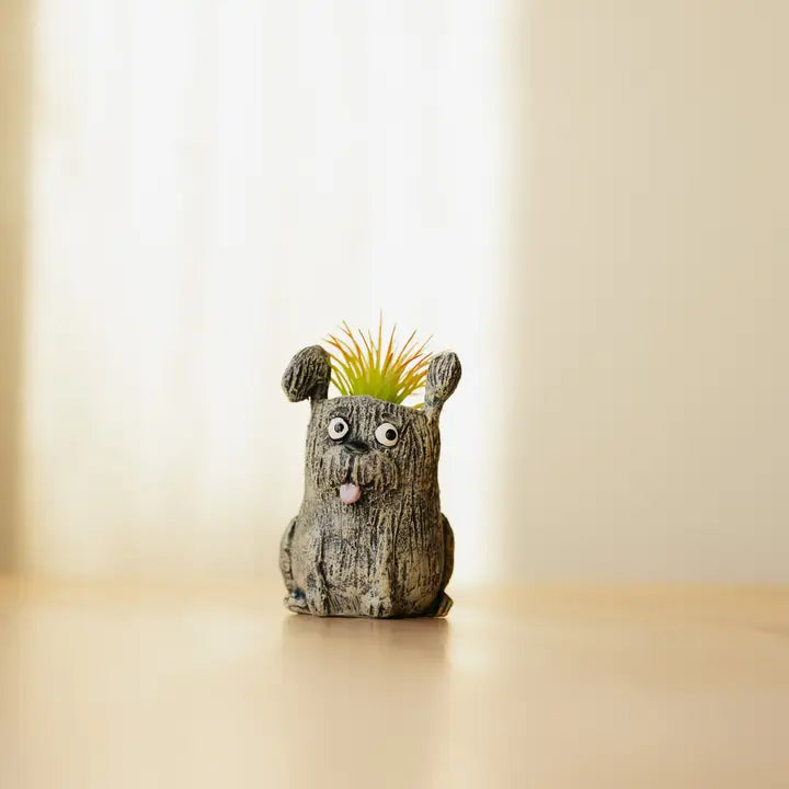 Ceramic dog-shaped planter with a small plant on its head against a plain background