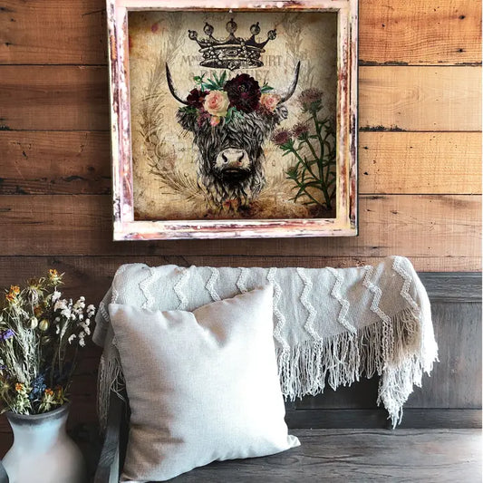 Decorative wall art of a cow with flowers on a wooden wall above a sofa.