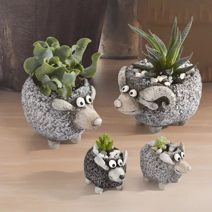 Four sheep-shaped planters with succulents on a wooden surface.