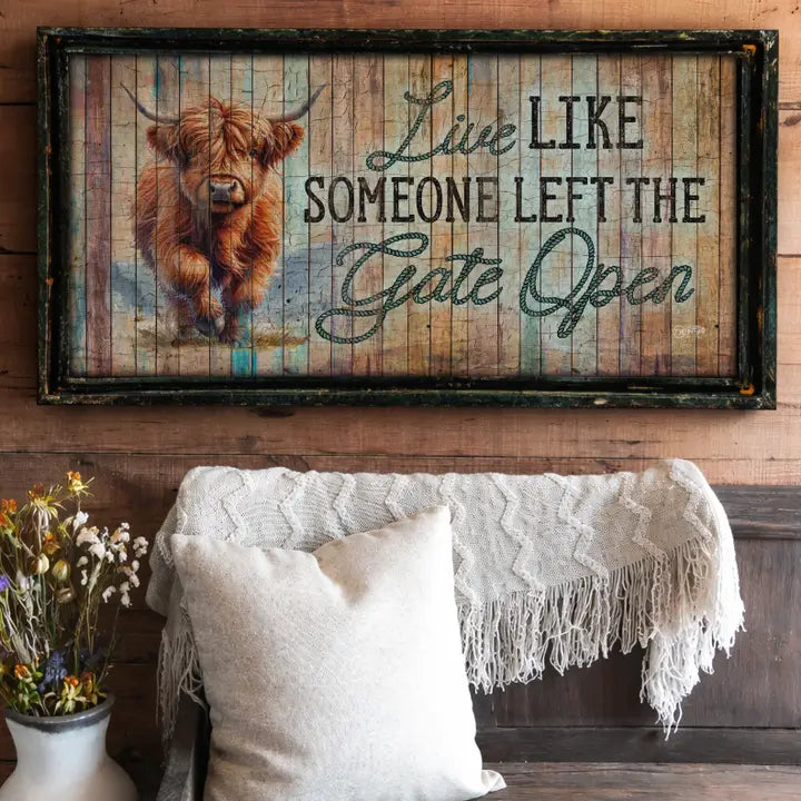 farmhouse wall art with a Highland cow and motivational quote on a wooden wall above a sofa.