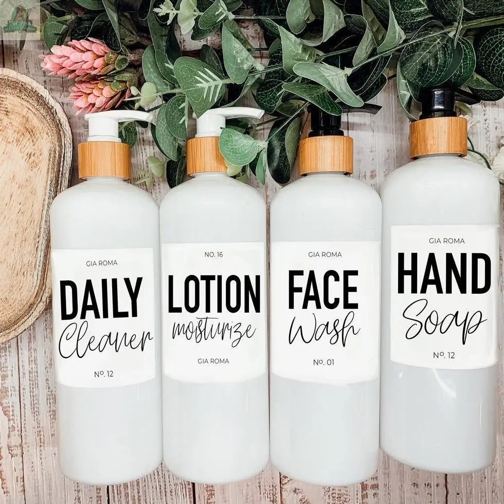 Four 16oz Plastic White bottles with white waterproof labels—Daily Cleaner, Lotion, Face Wash, and Hand Soap—stand side by side on a wooden surface, leafy plants in the background. Refillable dispensers ensure easy identification.