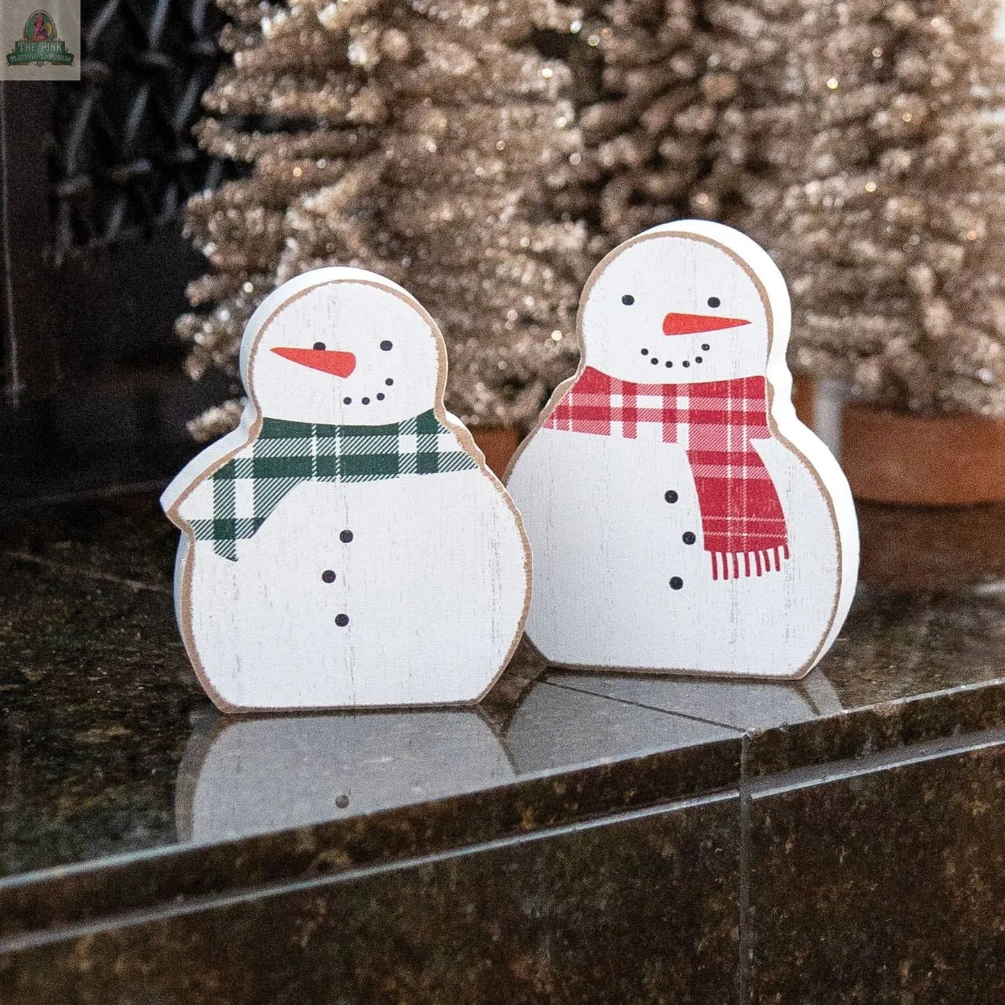 The 2/Set, Red & Green Scarf Wooden Snowman Sitters feature painted faces and plaid scarves, adding charming farmhouse holiday decor to any space beside glittery Christmas trees.