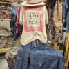 Vintage-style clothing with a shirt and pants on a wooden stand against a rustic background.