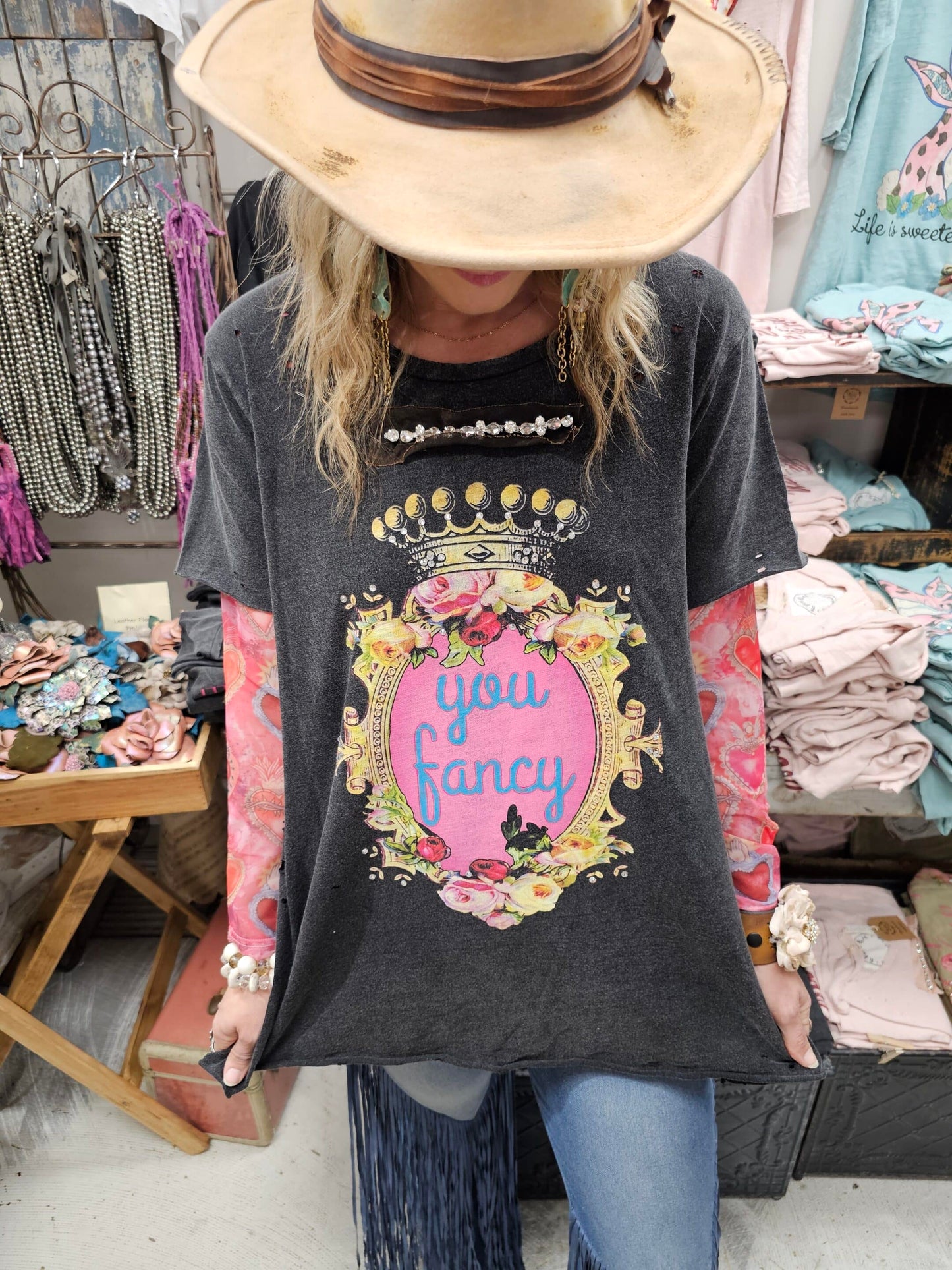 Person wearing a dark gray t-shirt with a colorful graphic and "you fancy" text, standing in a store setting.