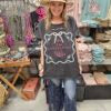 woman in a cowboy hat wearing a boho style tshirt with "unapologetically girly" on it