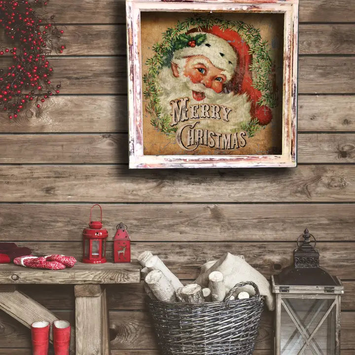 Framed Christmas-themed artwork with Santa Claus on a wooden wall.