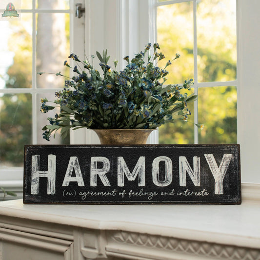 A 24" HARMONY METAL SIGN from Ragon House sits on a mantel before a vase of purple flowers, making it a perfect home decor piece. The sign reads: HARMONY (n.) agreement of feelings and interests.
