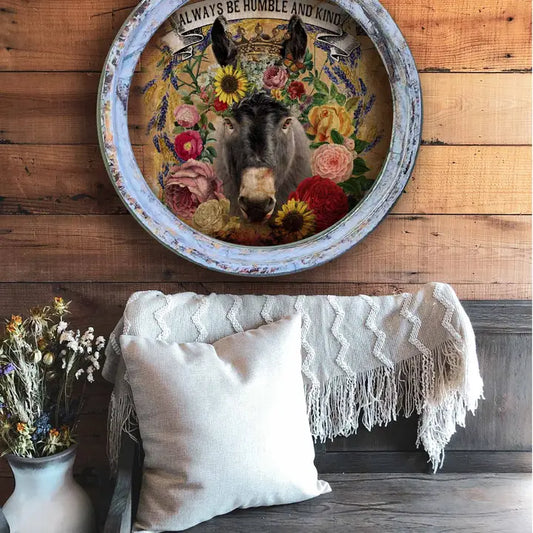 Decorative farmhouse wall decor with a donkey and floral design on a wooden wall above a sofa.