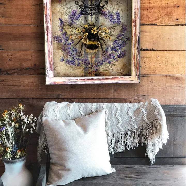 Decorative painting of a bee and flowers on a wooden wall above a sofa with pillows and a blanket.