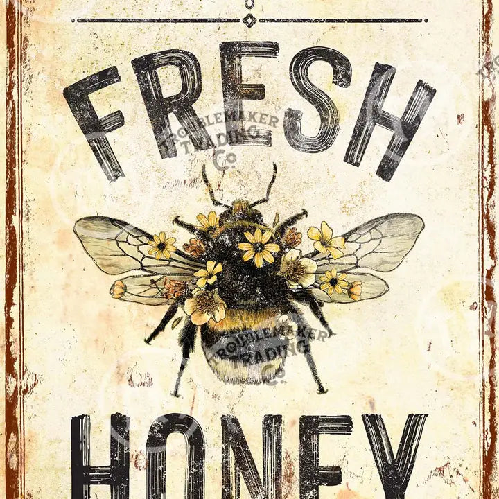 Vintage-style farmhouse wall art with a bee and flowers, featuring the text 'Fresh Honey' and 'Noleman Trading Co'.
