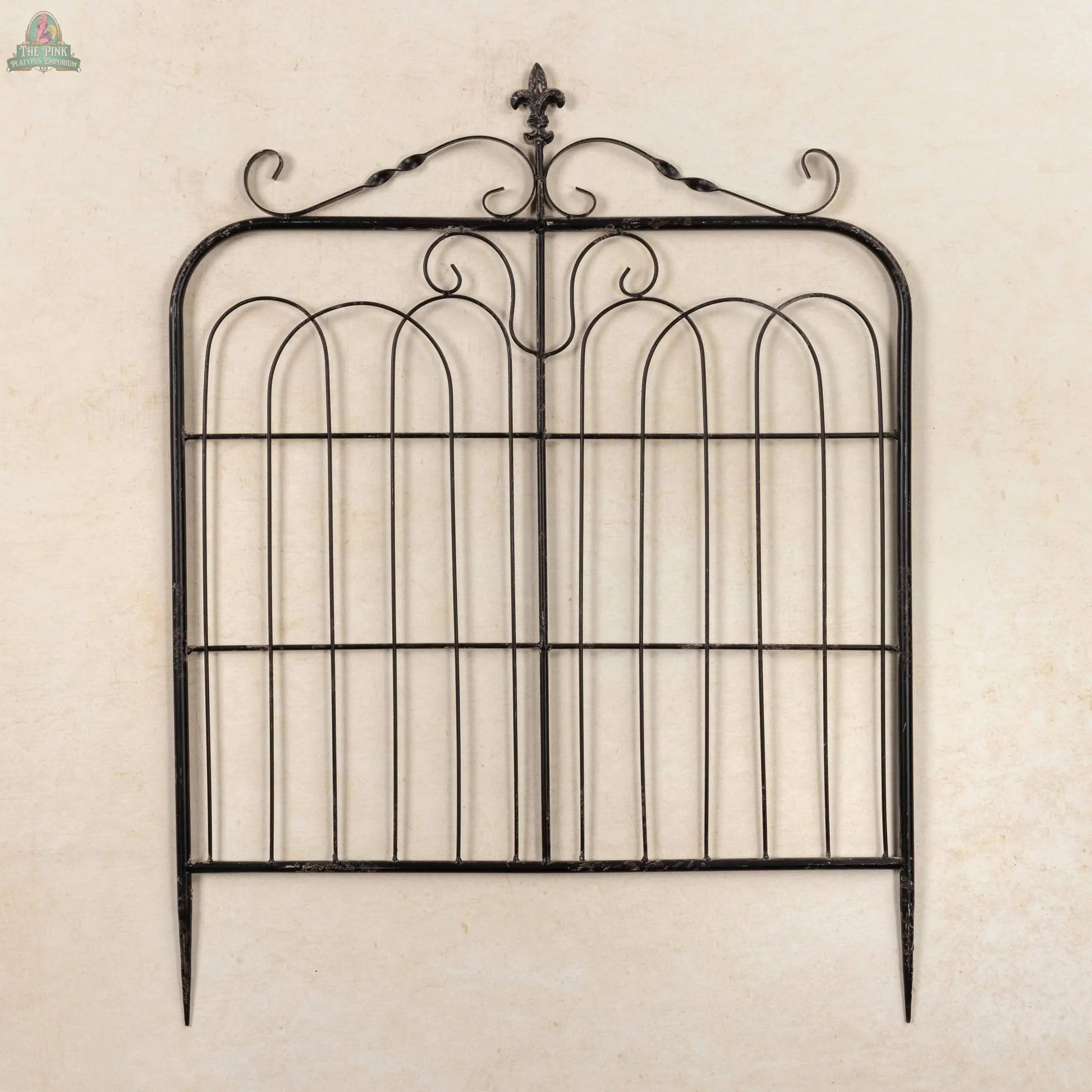The 32" Aged Black Garden Gate features decorative scrollwork, a fleur-de-lis top ornament, and is photographed against a plain beige background.
