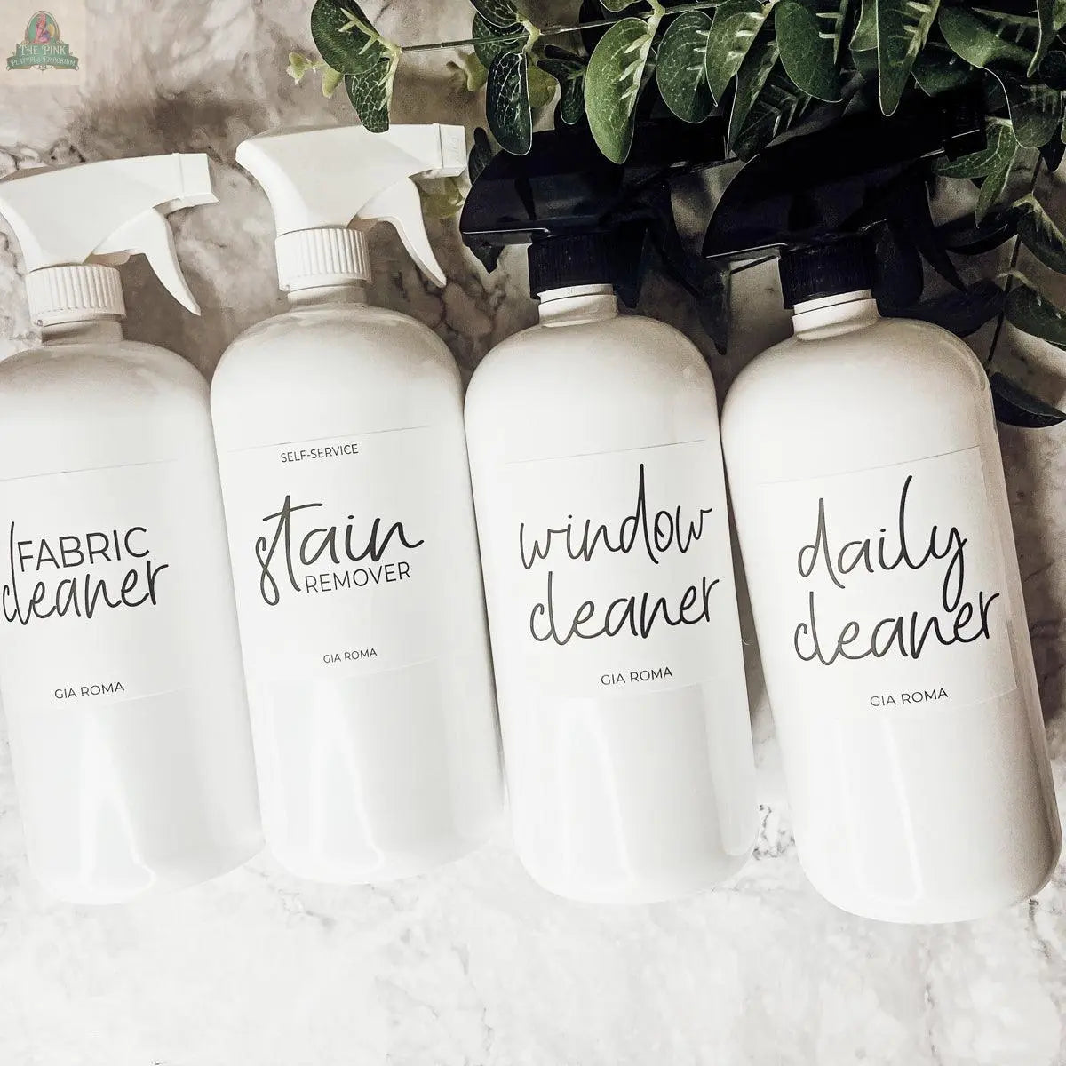 Four 32oz Plastic Cleaning Bottles labeled Fabric Cleaner, Stain Remover, Window Cleaner, and Daily Cleaner are arranged on a marble surface, featuring waterproof labels with green leaves at the top of the image.
