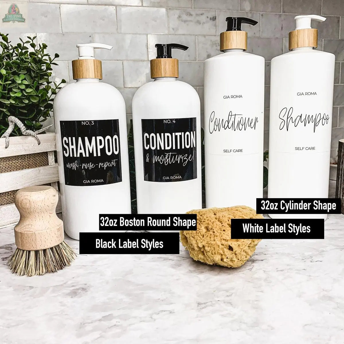 Four 32oz Plastic White Dispensers with black and white waterproof labels for shampoo, conditioner, and self-care products are displayed on a counter with a brush, sponge, basket, and plant. Labels show different styles and bottle shapes.