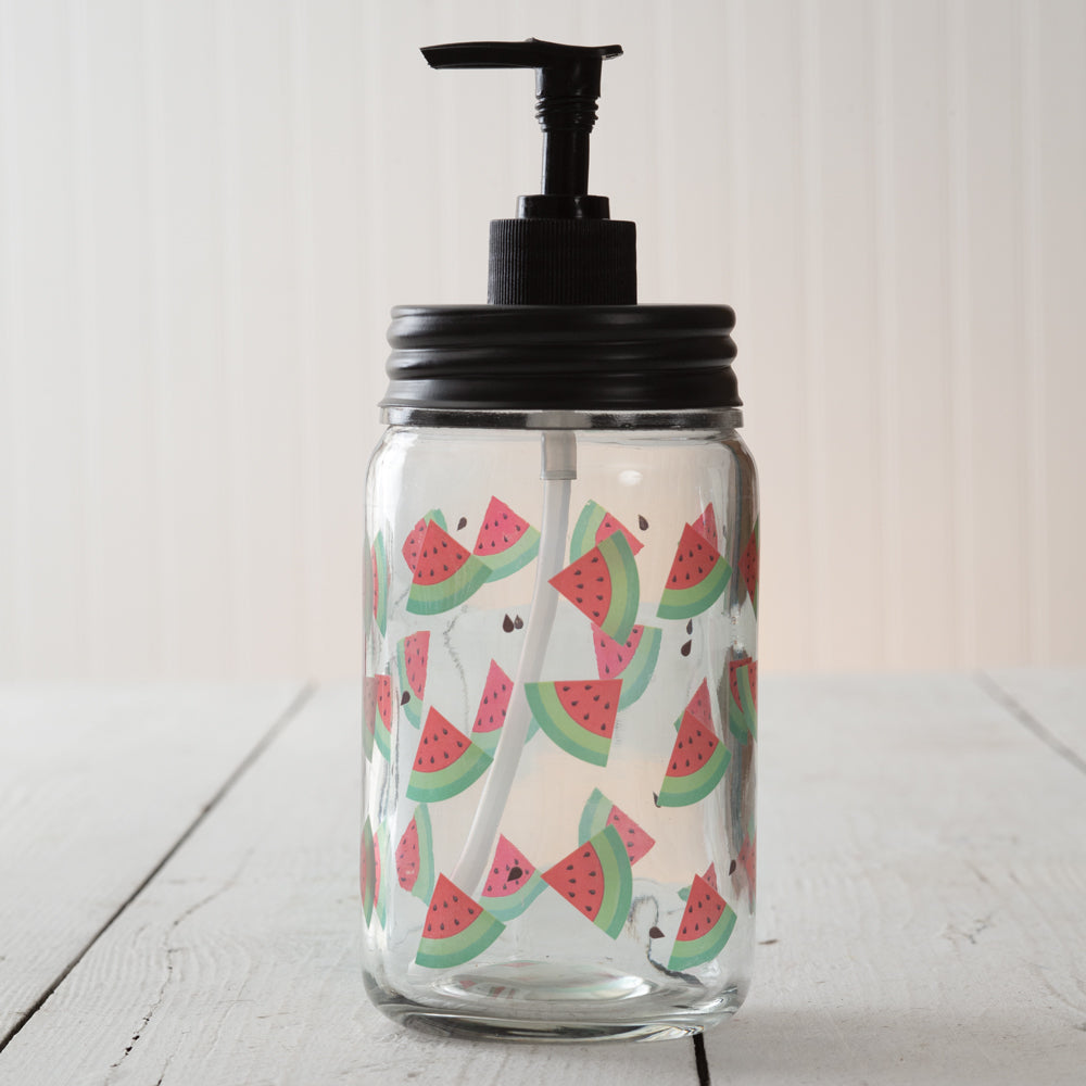 Glass dispenser with black pump and watermelon pattern on a white surface