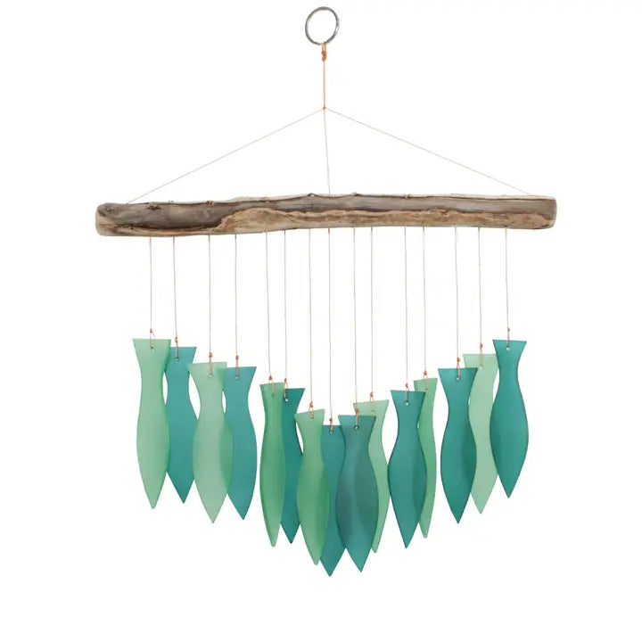 Teal fish-shaped wind chime hanging from a wooden branch on a white background