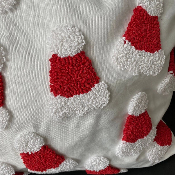 Close-up of red and white textured shapes resembling Santa hats on a white fabric background.