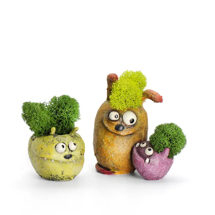 Three decorative monster-shaped planters with moss on a white background