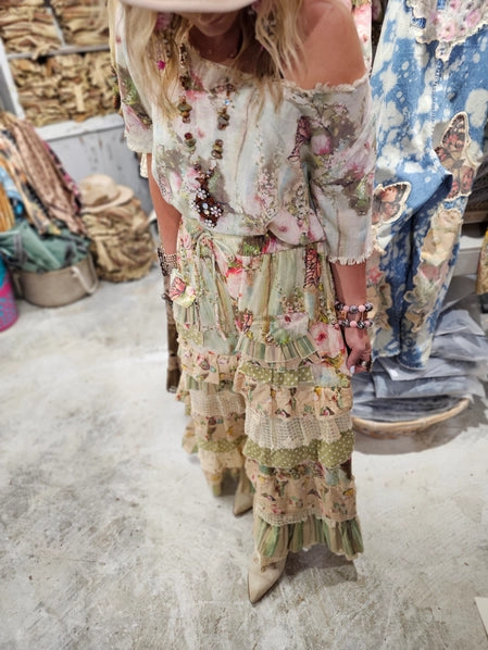 Woman in bohemian wide leg pants standing in a store with clothing racks and decor. - side view