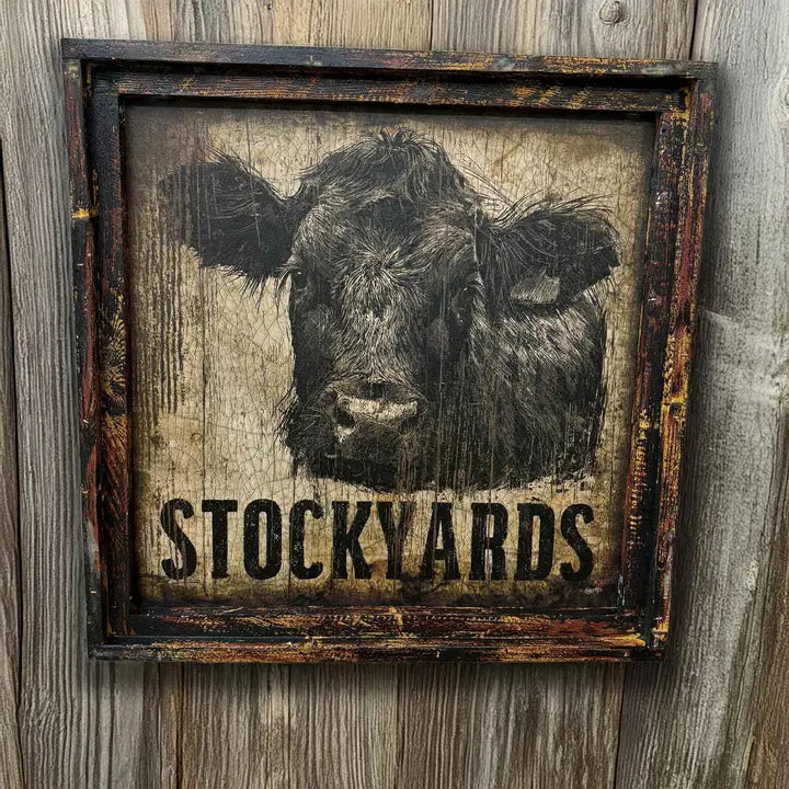 Framed artwork of a cow's face with 'STOCKYARDS' text on a wooden background