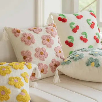 Decorative pillows with floral and cherry designs on a white surface.