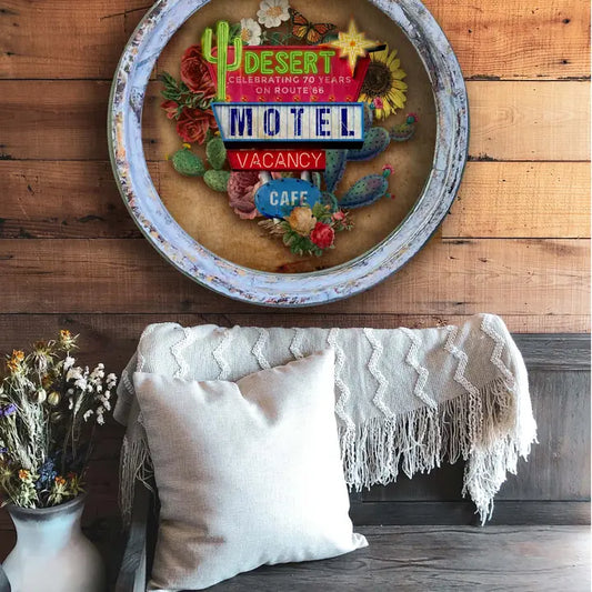 Decorative farmhouse wall decor of a vintage motel sign on a wooden wall above a couch with pillows and a blanket.