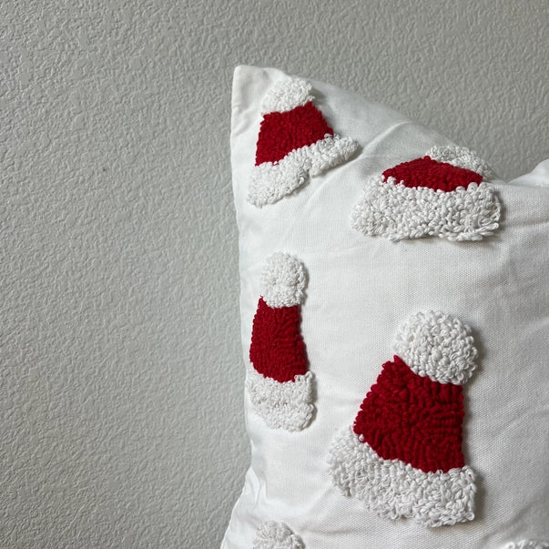 Decorative pillow with red and white Santa hat patterns on a plain background