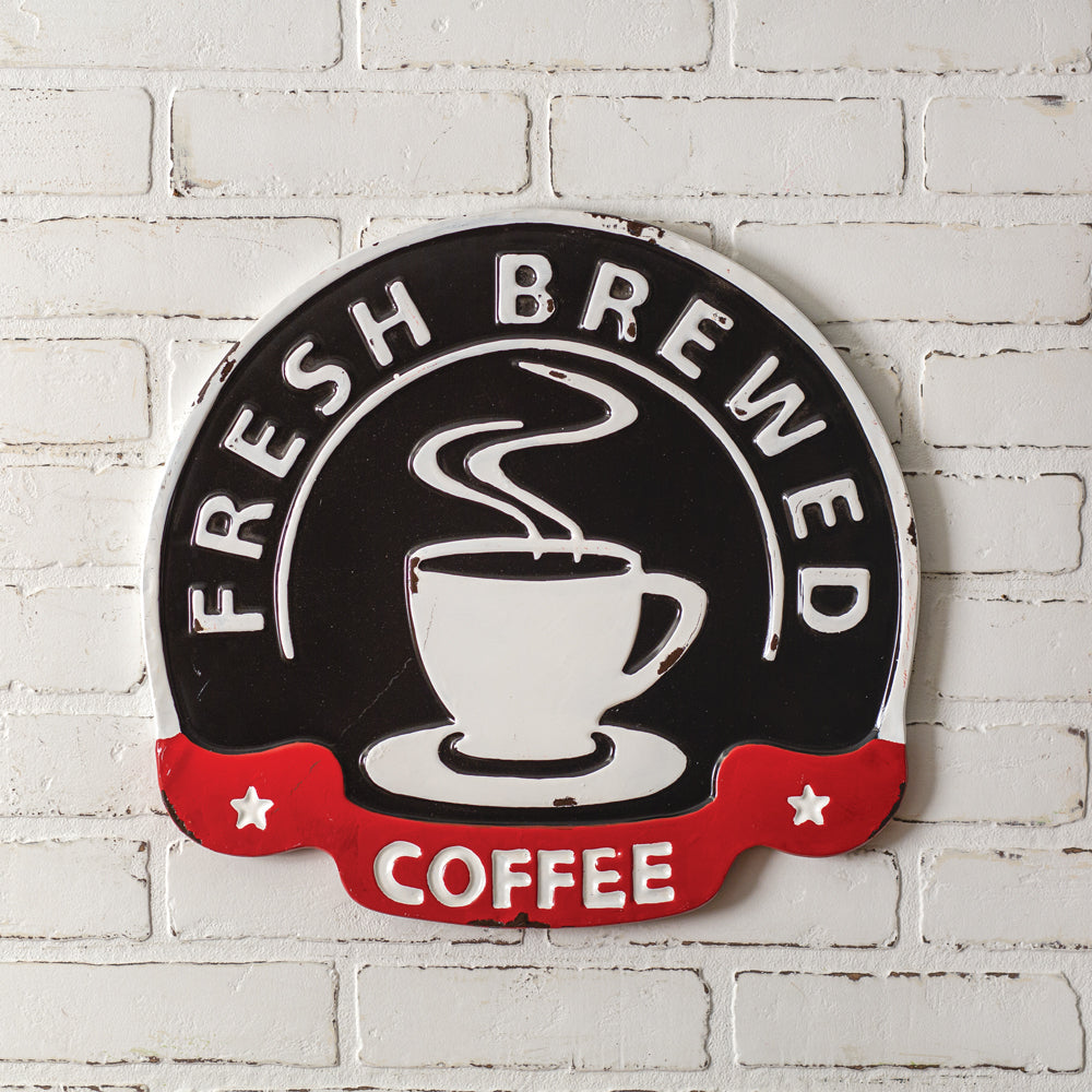 Decorative sign with 'Fresh Brewed Coffee' text and a coffee cup graphic on a white brick wall.