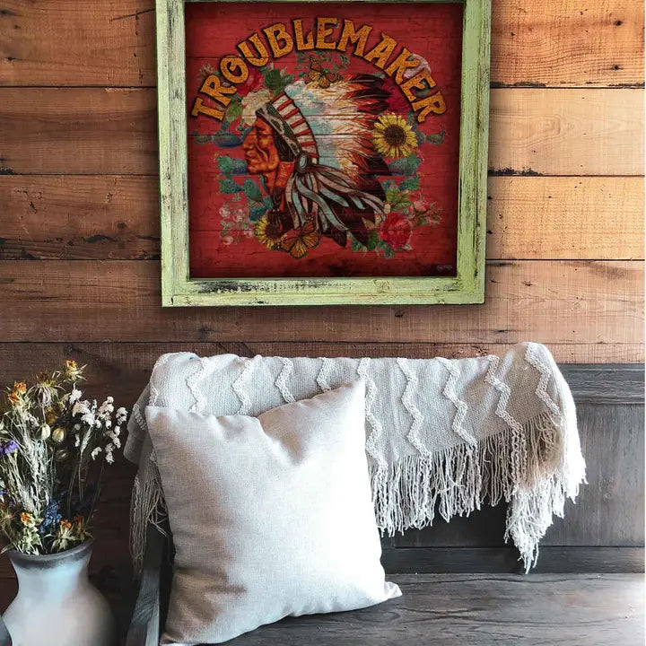 Decorative wall art with 'Troublemaker' on a wooden wall above a sofa.