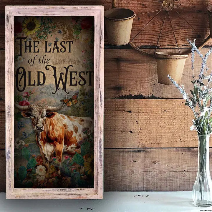Western wall art with a longhorn cow and text 'The Last of the Old West' in a rustic setting.